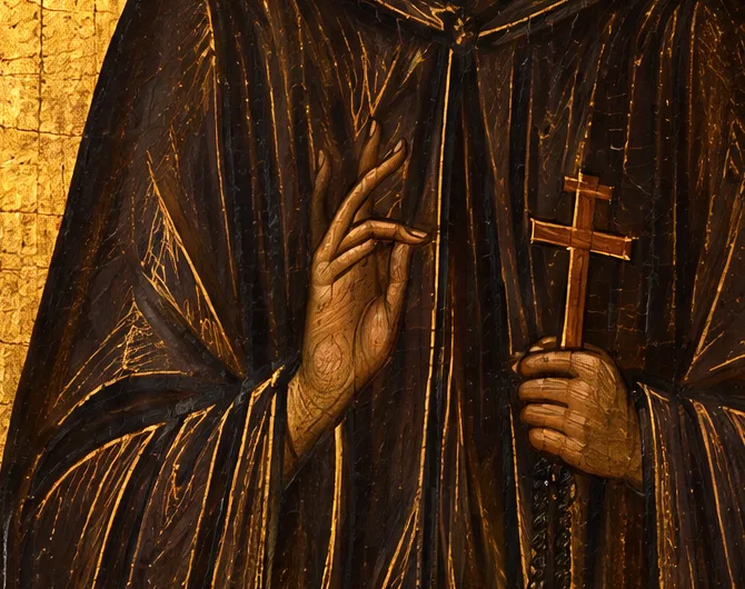 The right hand raised in blessing and the left holding a small wooden cross